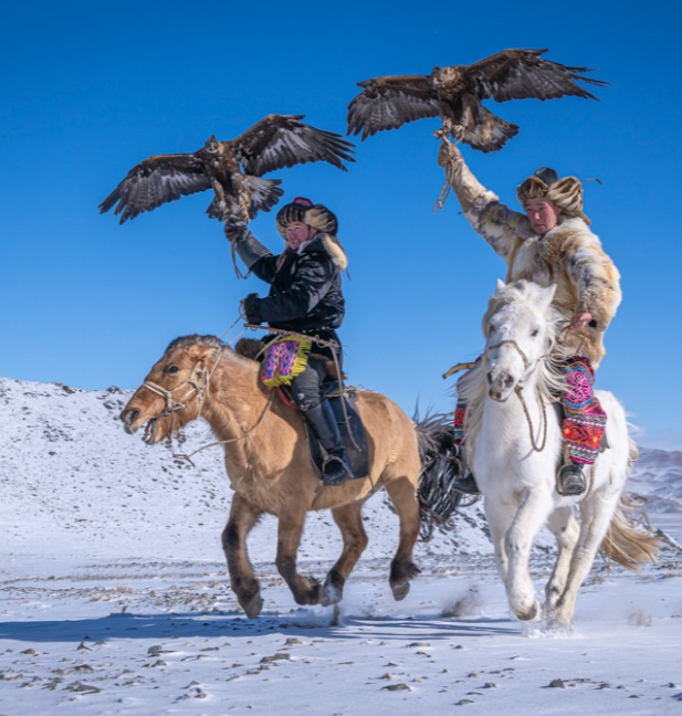 <i>Mongolian eagle hunters riding horses and wearing traditional clothing</i>